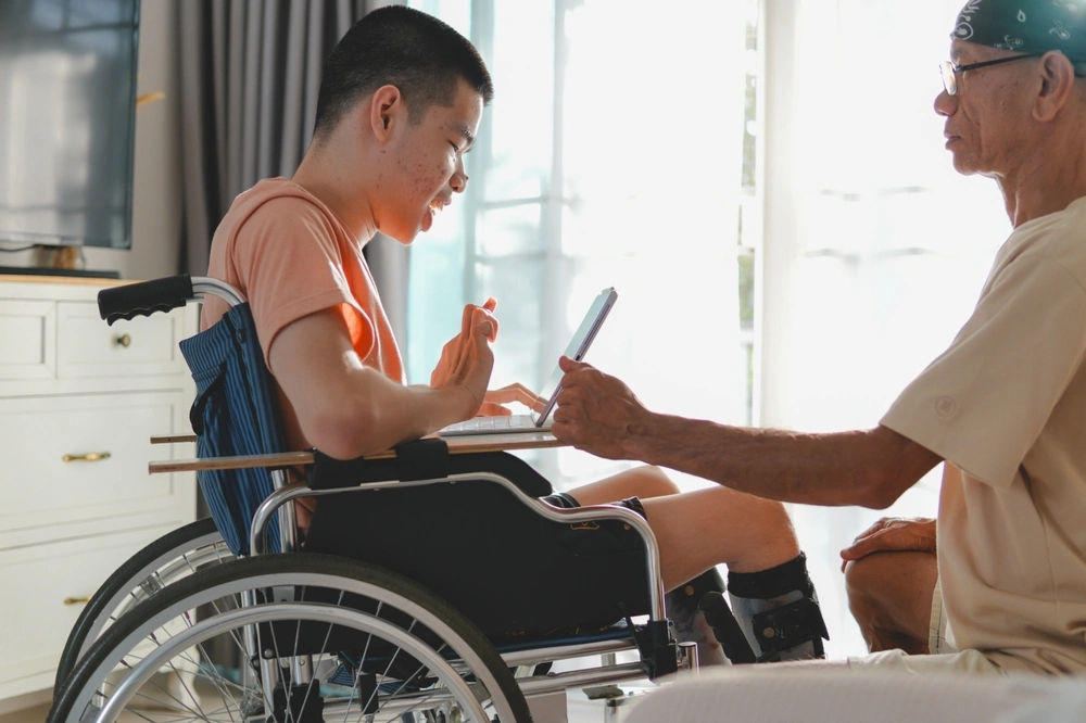 caretaker helping young boy with down syndrome and on wheelchair
